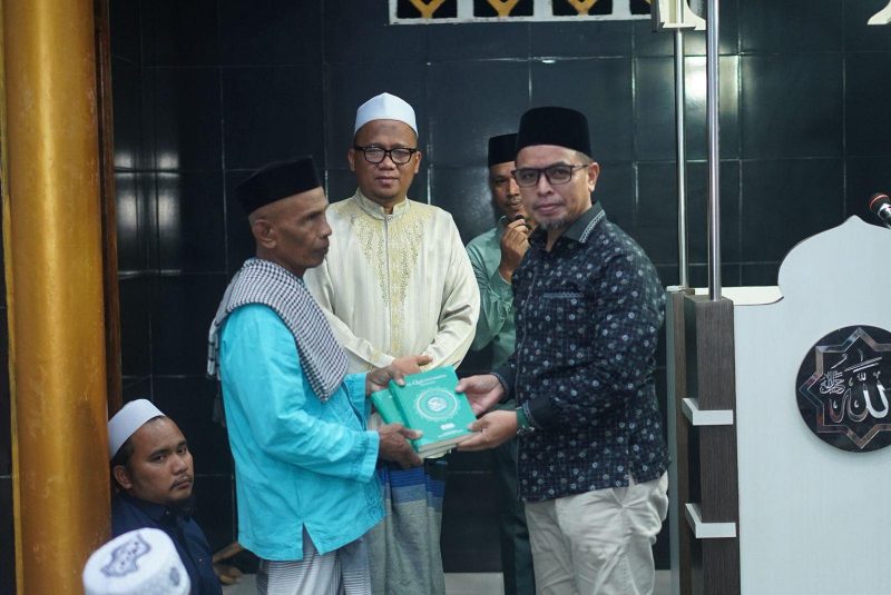 Dr.Sirajudin Lasena Menyerahan Al-Qur’an kepada imam masjid Al-Hidayah desa Kuala, kecamatan Kaidipang. 